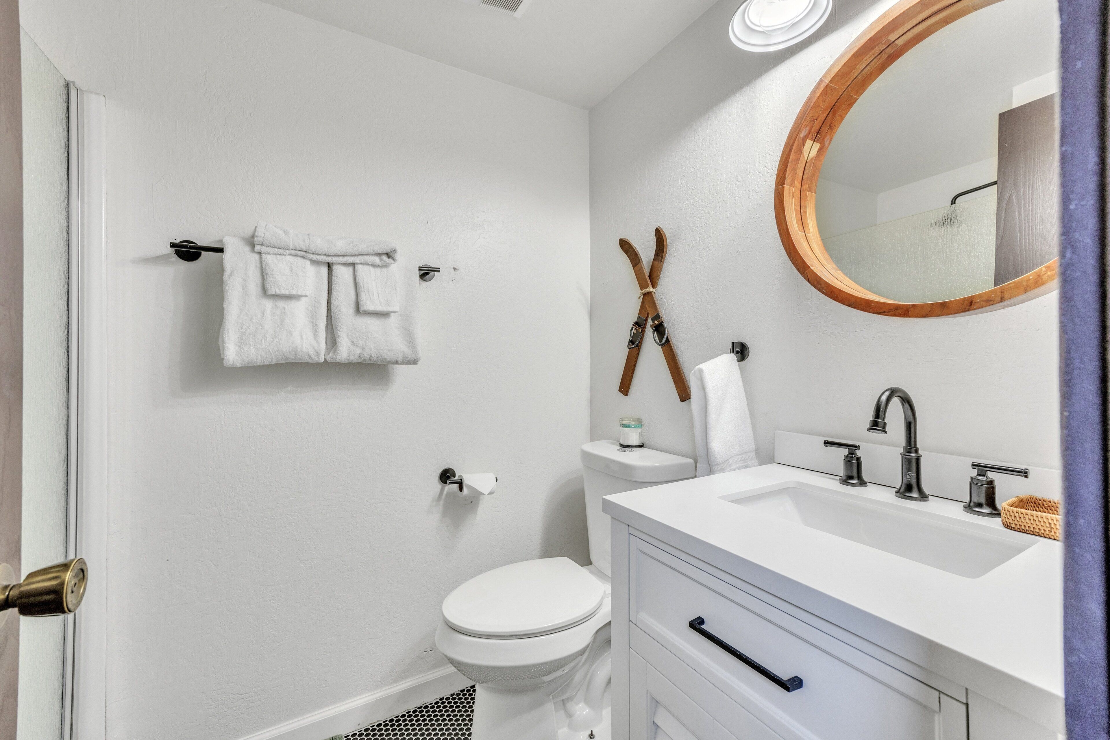 A bathroom with a white sink, a mirror, and a toilet.