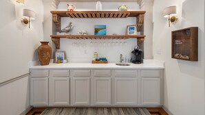 Eine Küche mit weißen Schränken, einer Holz Arbeitsplatte und einem eingebauten Weinkühlschrank.