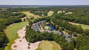 An aerial view of a golf course with a clubhouse, a swimming pool, and surrounding wooded areas. - 65d Isle Awhile 3 Bedroom Condo (Pawleys Island)