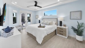 Ein modernes Schlafzimmer mit einem großen Bett, Nachttischen, einem Deckenventilator und einem Fenster mit Blick.