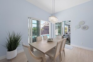 A dining area with a table, chairs, a chandelier, and a potted plant.