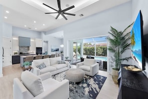 A spacious living area with a large sofa set, a dining table, and a kitchen in the background.