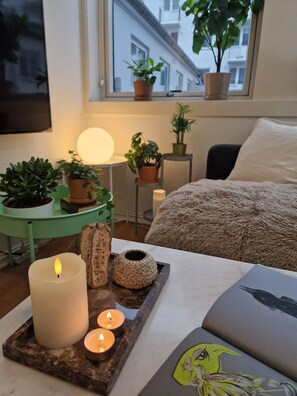 Et hyggeligt soveværelse med seng, et natbord med lampe og et vindue med planter.
