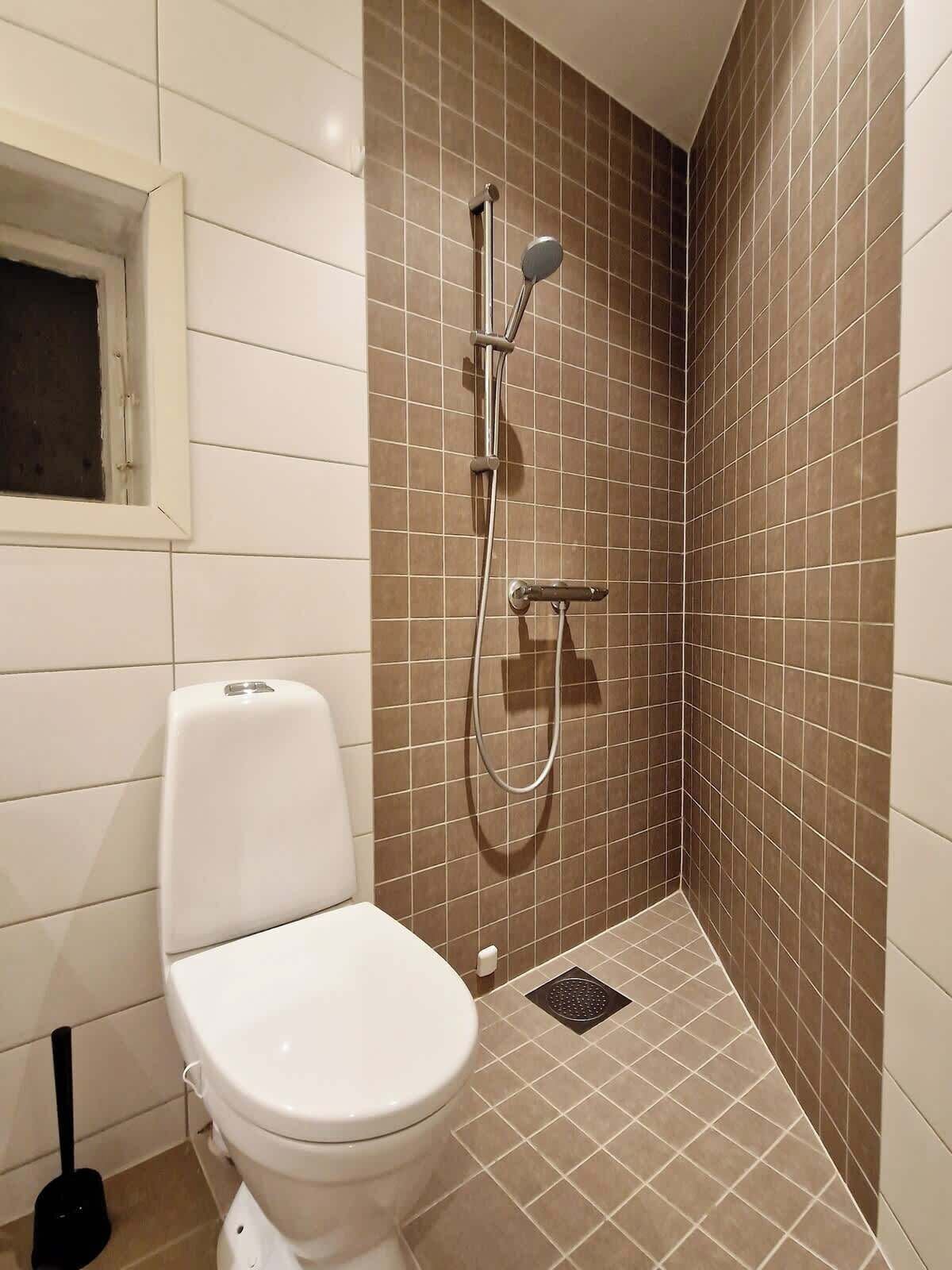 Kylpyhuone, jossa on wc, suihku ja ikkuna.