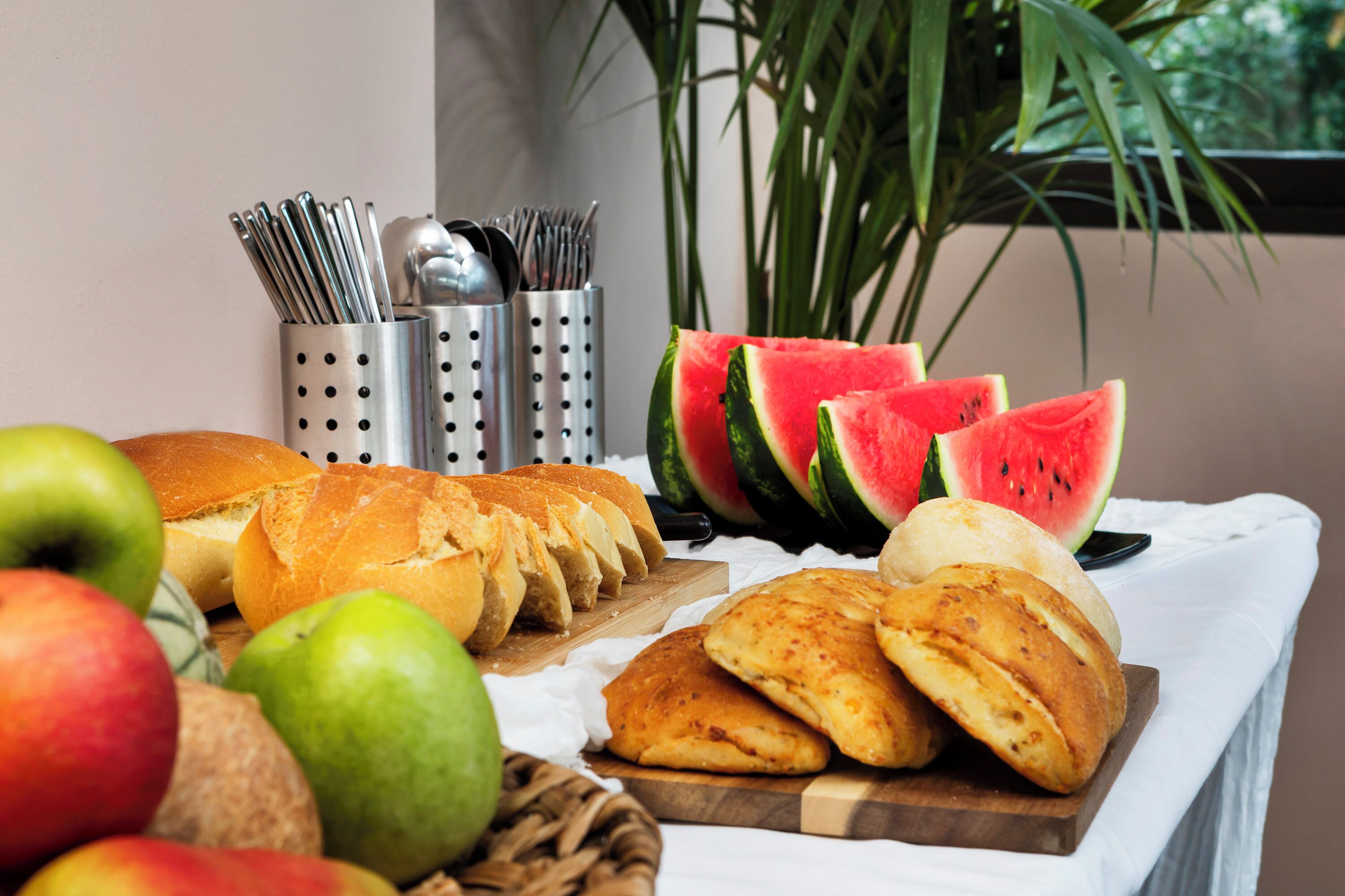 Een tafel met brood, appels en stukken watermeloen.