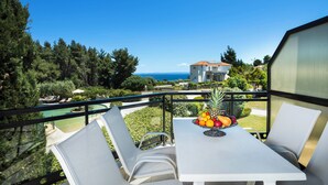 A balcony with a table set for two, overlooking a pool and a view of the sea. - Ohana Hotel (Kassandra)
