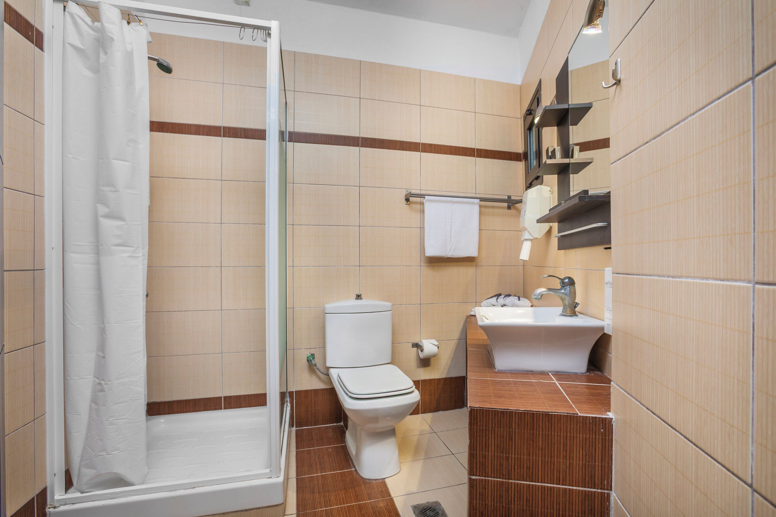 A bathroom with a shower, toilet, sink, and towel rack.