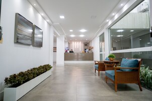 Uma área de recepção moderna com balcão, espaço para sentar e plantas em vasos.