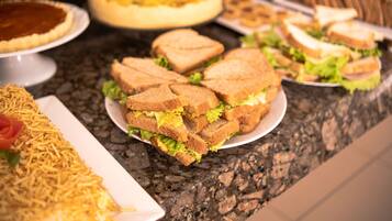 Una mesa de buffet con diversos platos, incluyendo sándwiches, una quiche y una ensalada.