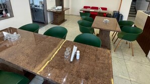 Ein moderner Essbereich mit einem Marmortisch, grünen Polstersesseln und einer Decke mit Einbautenbeleuchtung.