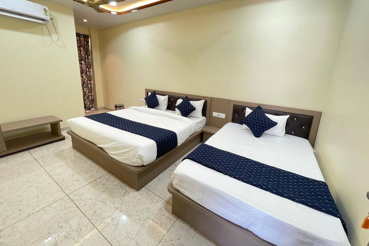 A hotel room with two beds, a ceiling fan, and an air conditioning unit.