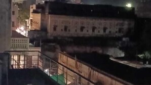 Ein Nachtbild eines Gebäudes mit einer Dachterrasse, einer Treppe und einer grünen Plane, die einen Teil des Geländes bedeckt.