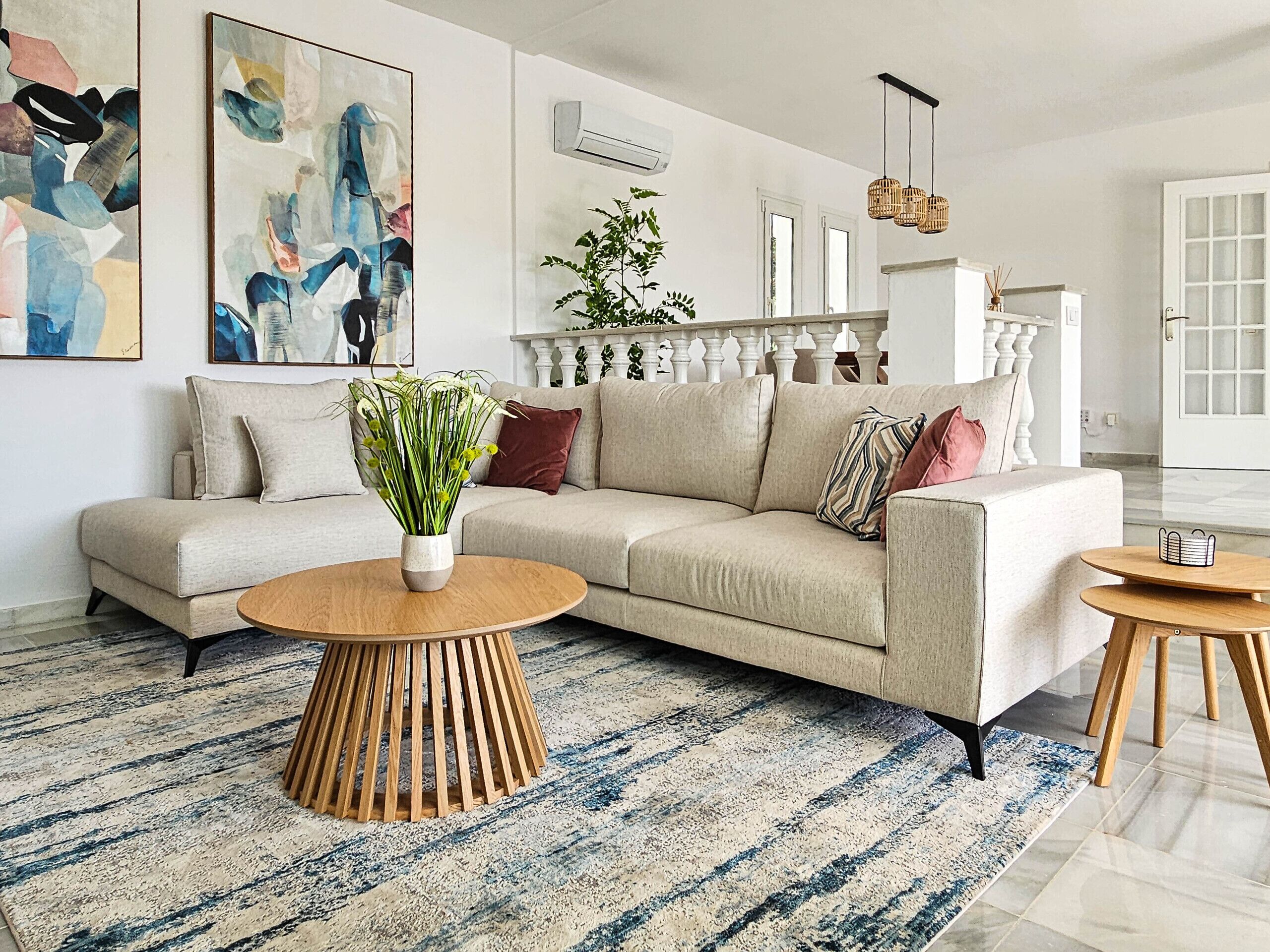 A modern living room with a beige sofa, a wooden coffee table, and a striped area rug.