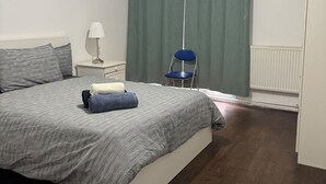 A bedroom with a bed, a chair, a nightstand, a lamp, and a radiator. - Calm and Cosy Apartment in Central London (London)