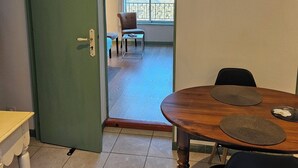Une pièce comprenant une table à manger en bois, une chaise et donnant sur un balcon équipé d’une chaise et d’une table.