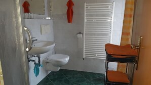 Ein Badezimmer mit Waschbecken, Toilette und Handtuchhalter mit Handtüchern.