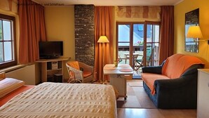 Ein Hotelzimmer mit einem Bett, einem Schreibtisch, einem Sessel, einer Couch und einem Fernseher.