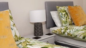 A hotel room with two beds, each with a leaf-patterned bedspread, a grey headboard, and a white nightstand with a lamp. - Location! Location! Location! A Golf Lover’s Dream (St Andrews)