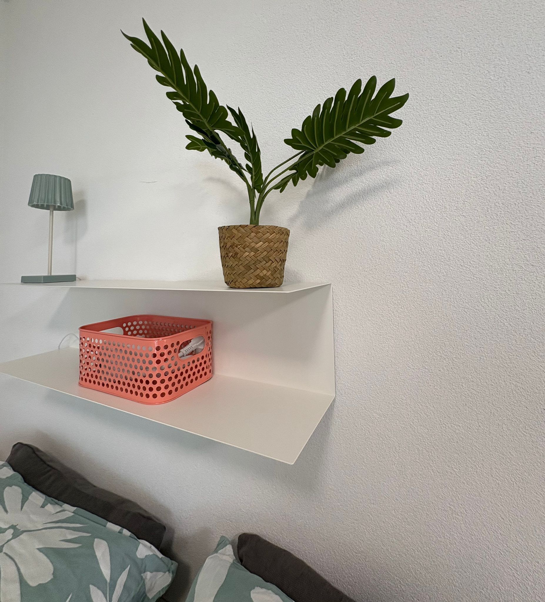 A white shelf with a woven basket and a potted plant.