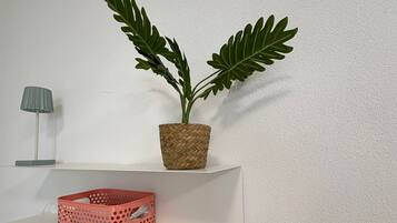 A white shelf with a woven basket and a potted plant.