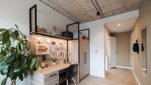 A modern office space with a wooden desk, black chair, and a potted plant. - Student Only Old Kent Road (London)