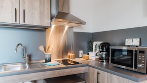 A modern kitchen with stainless steel appliances, wooden cabinets, and a built-in oven. - Student Only Old Kent Road (London)