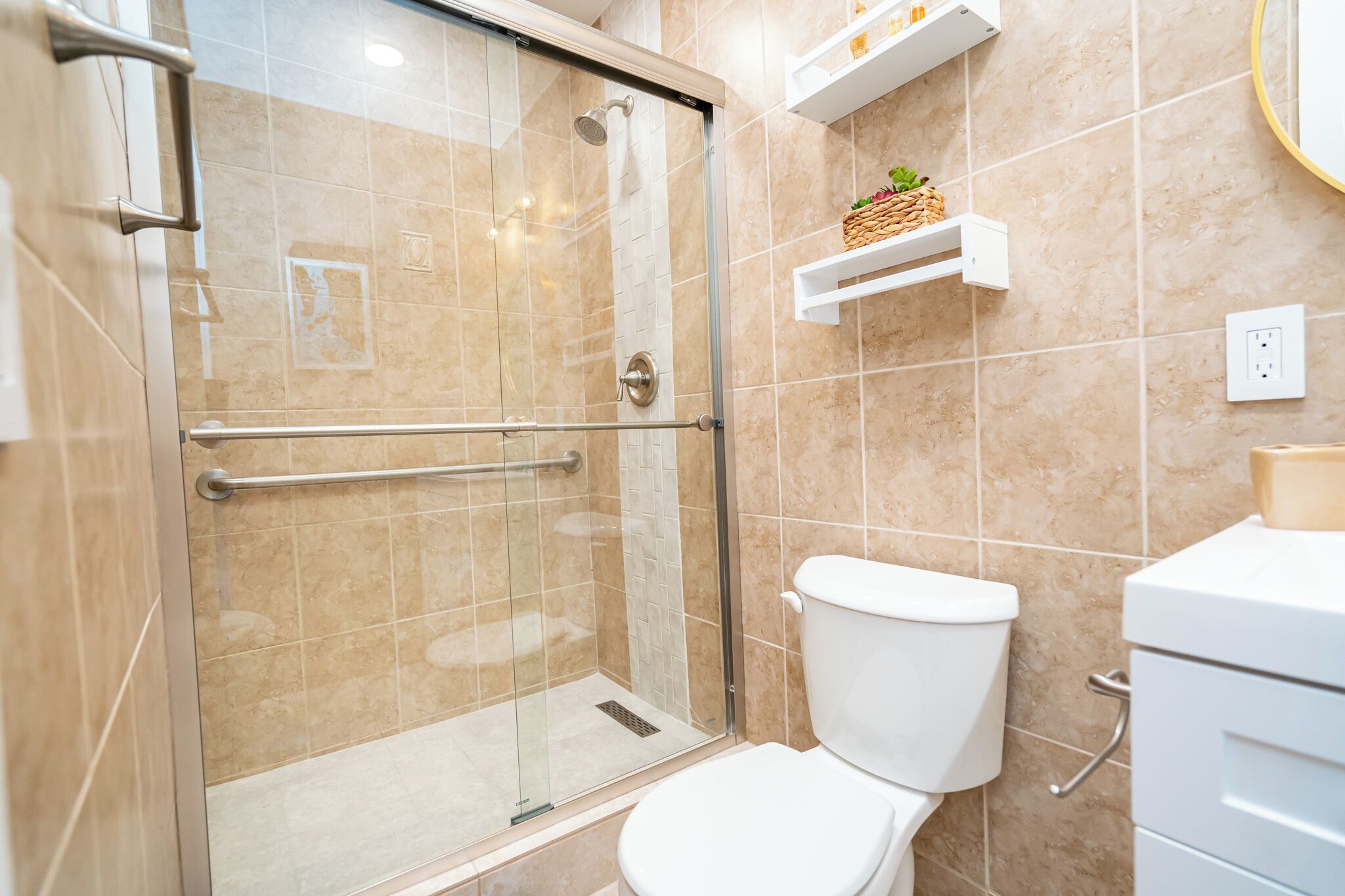 Een badkamer met een douchecabine van glas, een wit toilet en een witte wastafel.