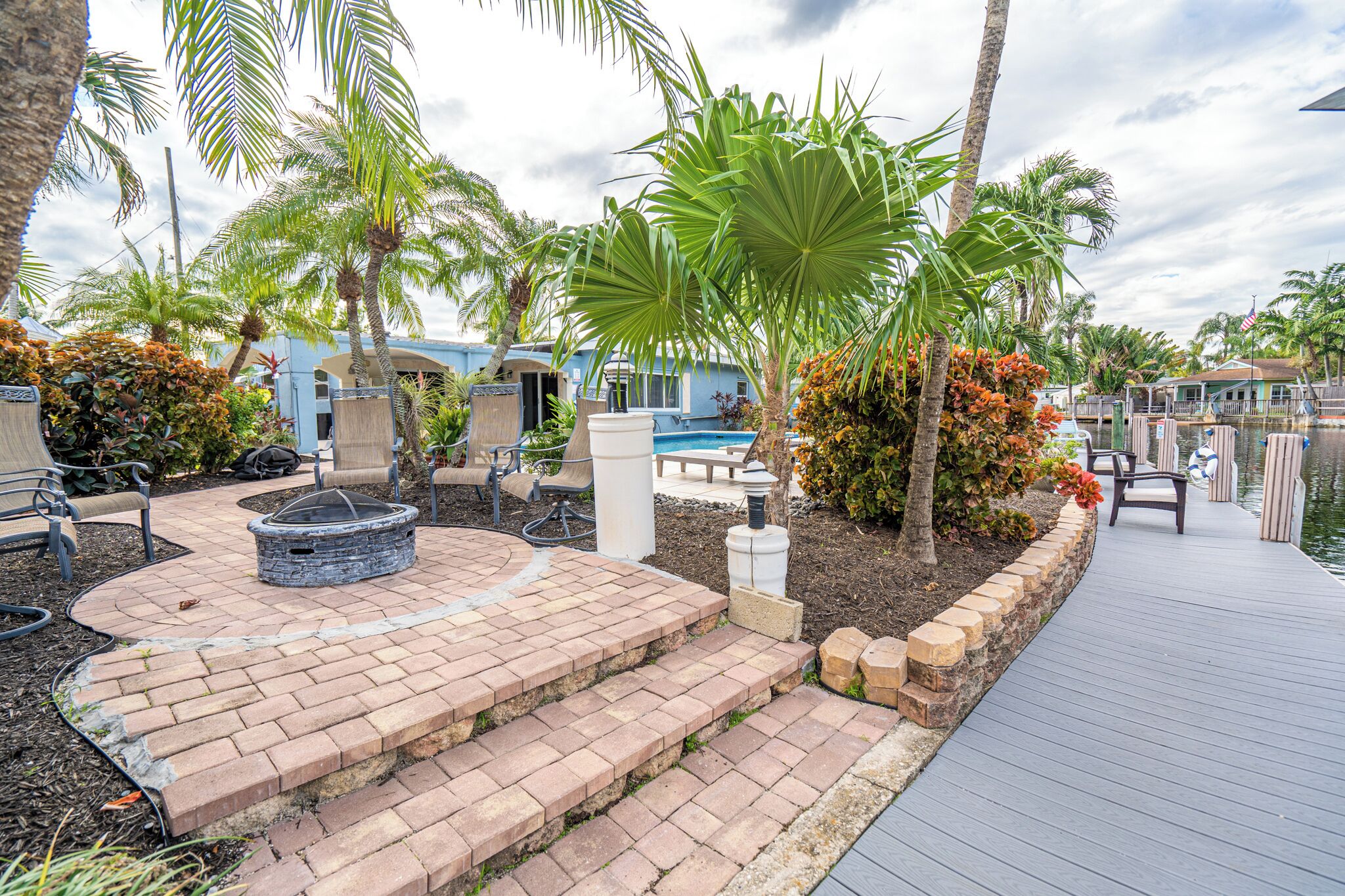A patio area with a fire pit, outdoor seating, and a poolside deck.