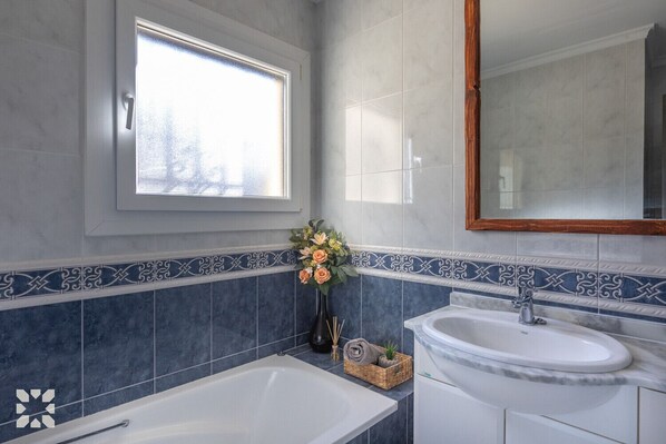 A bathroom with a bathtub, a sink, and a window.