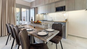 A modern kitchen with a built-in microwave, a fruit bowl, and a dining area with a table set for four. - Villa Oasis in Nikiana - Sleep 6 - Pool - Hot Tub (Lefkada)