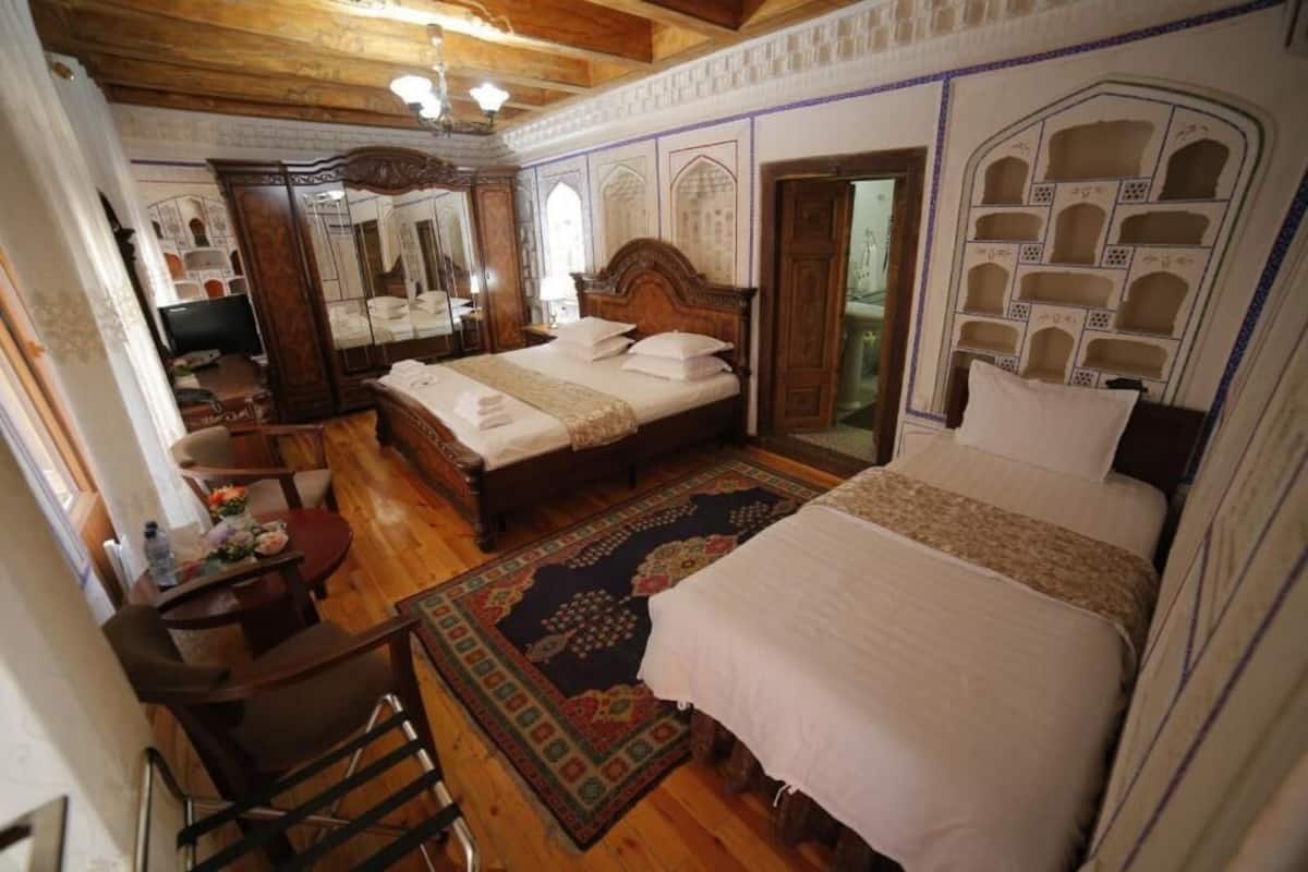 A traditional room with a large bed, a wooden desk, and a mirror.