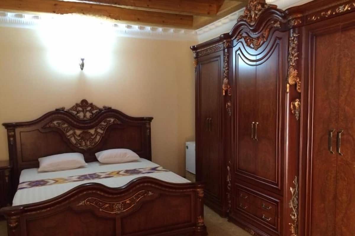 A bedroom with a large wooden bed, a wardrobe, and a bedside table.