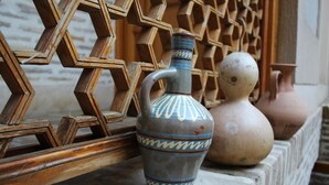 A wooden lattice structure with a vase and two pots on a stone ledge. - Kavsar Hotel (Bukhara)