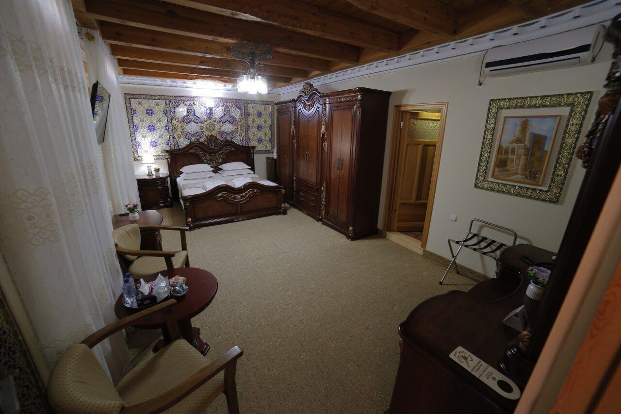 Een slaapkamer met een houten bed, een kledingkast, een stoel en een klein tafeltje.
