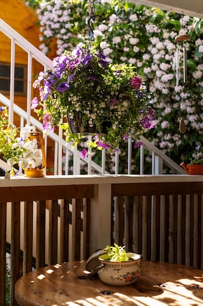 A wooden deck with a hanging flower basket, a potted plant, and a lantern.