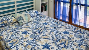 A bedroom with a bed, a white nightstand, a blue wall, and a window with blue curtains. - Apartment with access to the Costa dei Trabocchi bike path (ortona)