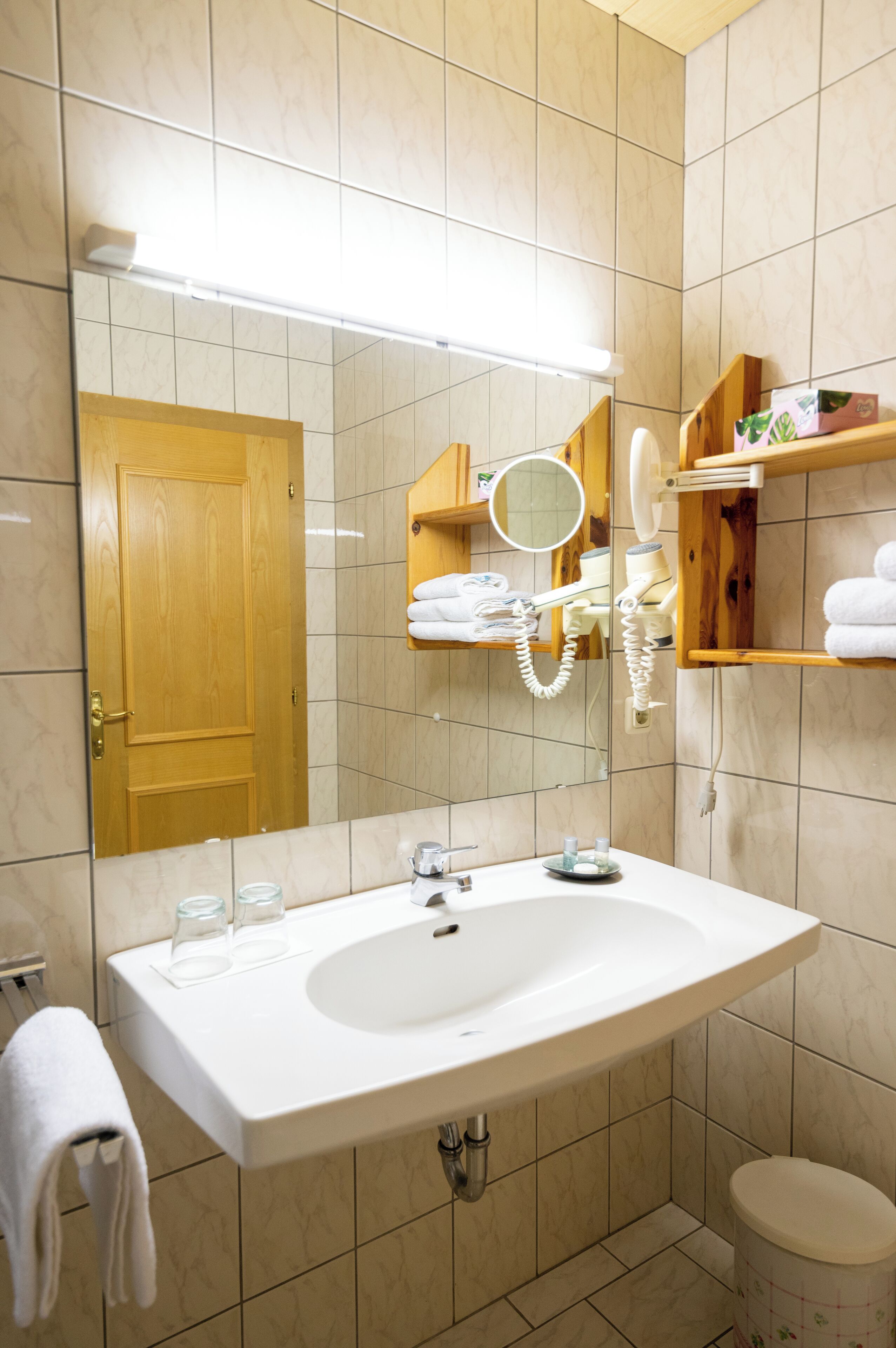 A bathroom with a large mirror, a sink, a towel rack, and a toilet.