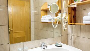 A bathroom with a large mirror, a sink, a towel rack, and a toilet.
