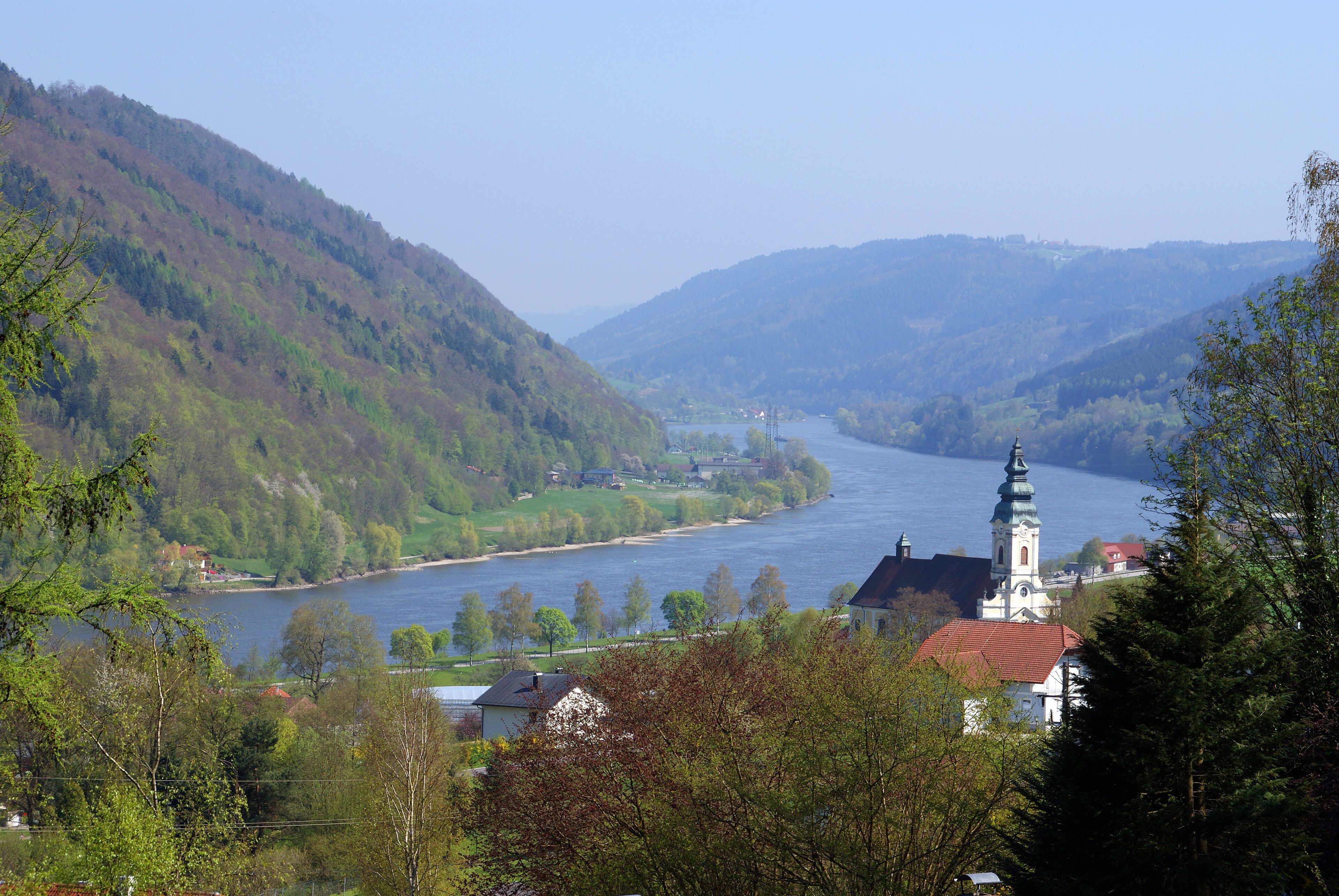 A river valley with a church and residential buildings.