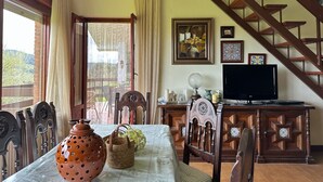 Un comedor con una mesa preparada para dos, una escalera de madera y un televisor sobre un mueble de madera.