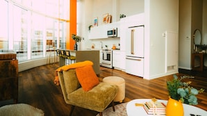A modern living room with a sofa, ottoman, and a small table with books and a vase. - *Penthouse* - Luxe Stay with Views - Free Parking (Halifax)