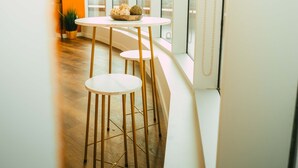 A modern dining area with a curved white table and wooden chairs, large windows, and a view of the outdoors. - *Penthouse* - Luxe Stay with Views - Free Parking (Halifax)