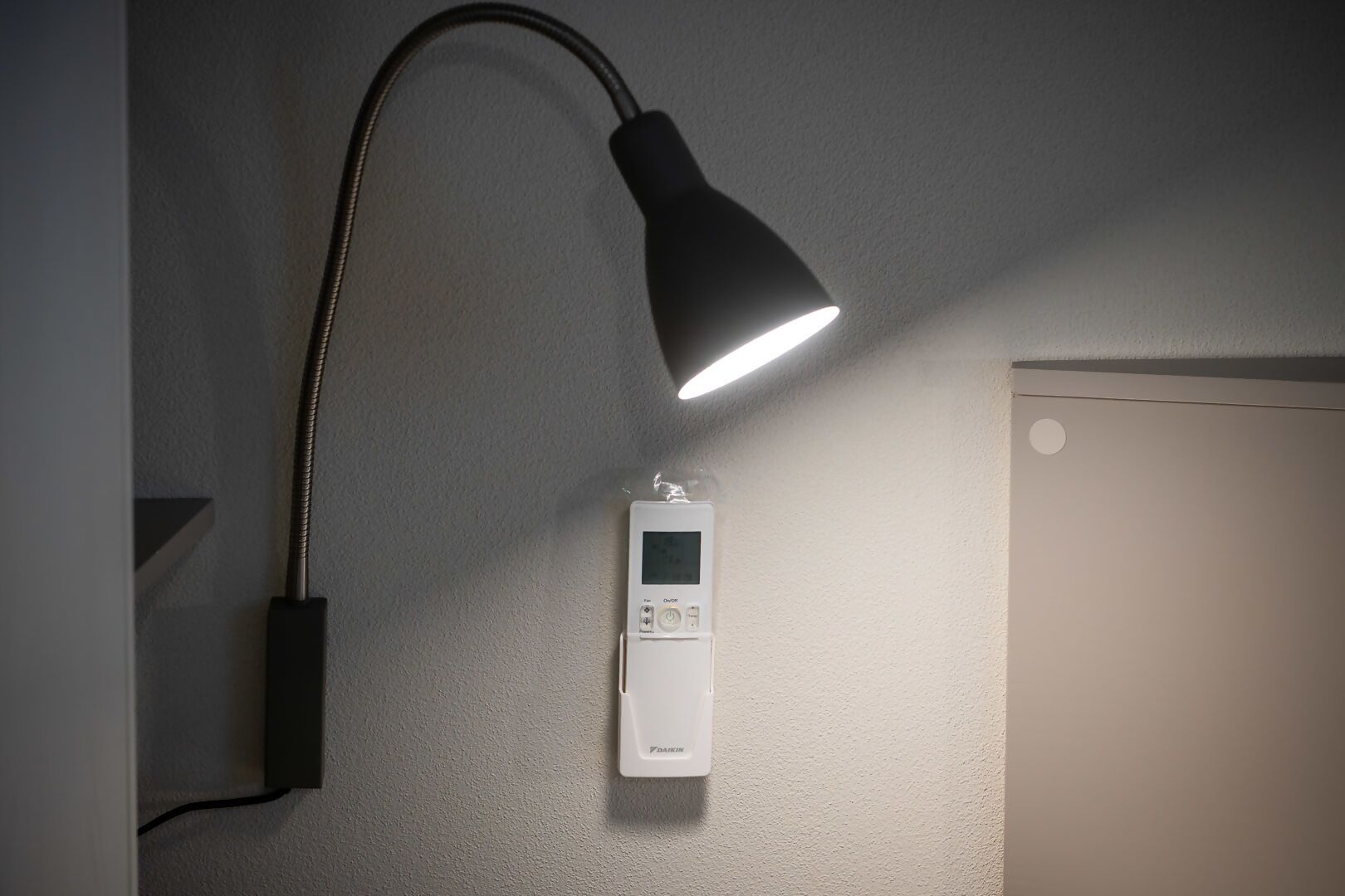 Um termostato fixado na parede, com painel de controle e uma lâmpada.