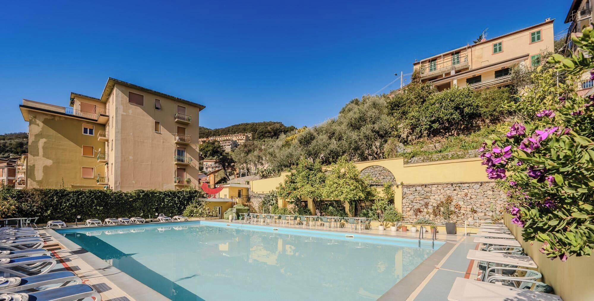 A swimming pool with lounge chairs and a stone wall.