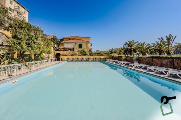 Una piscina al aire libre de temporada, sombrillas