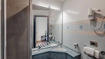 A modern bathroom with a large mirror, a shower, a sink, and a towel rack.