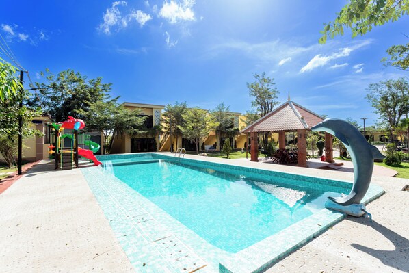 A swimming pool with a dolphin sculpture, a slide, and a gazebo.