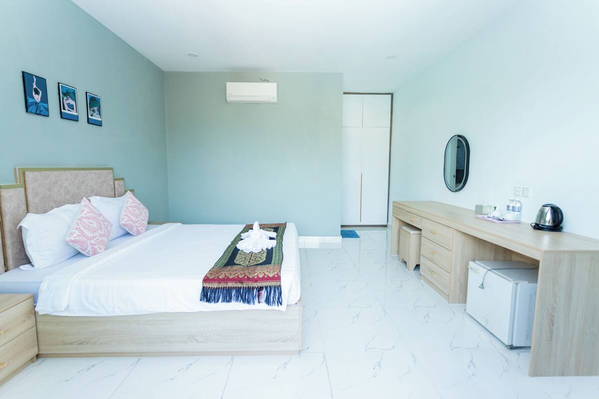 A bedroom with a bed, bedside tables, a desk, a mirror, and a wardrobe.