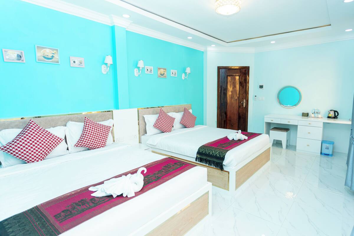 A hotel room with two beds, a desk, a mirror, and a door.