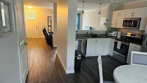 Una cocina moderna con gabinetes blancos, electrodomésticos de acero inoxidable y piso de madera oscura.